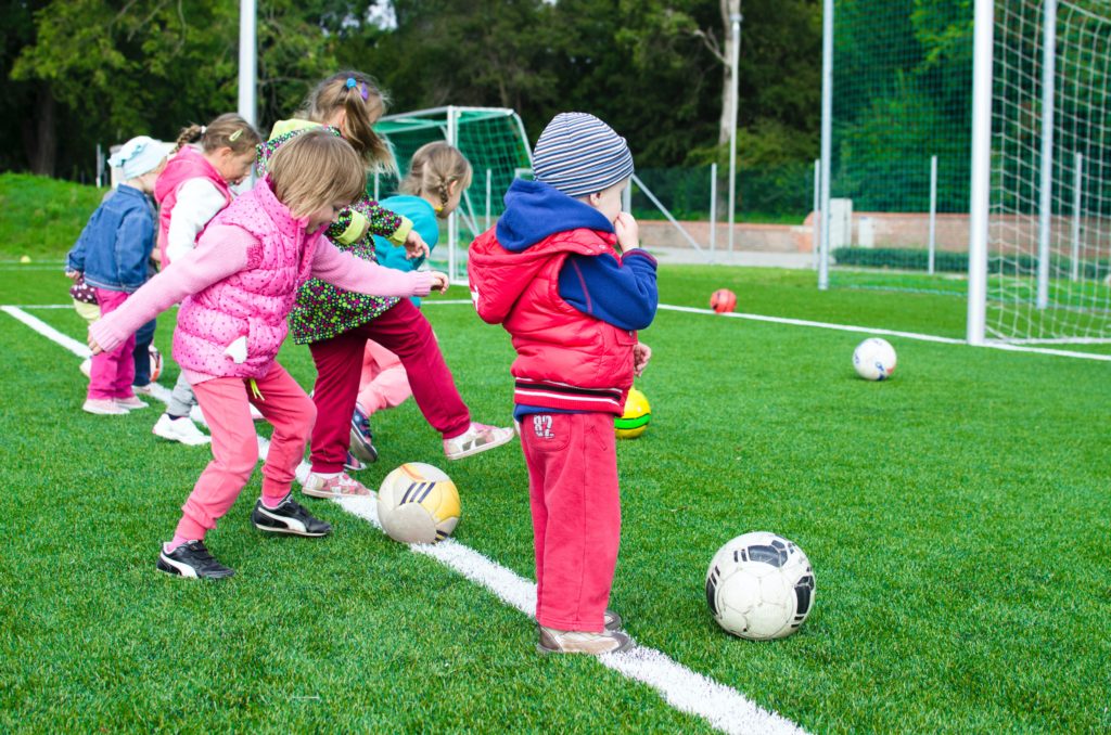 Kinder spiele Ball auf grünem Rasen